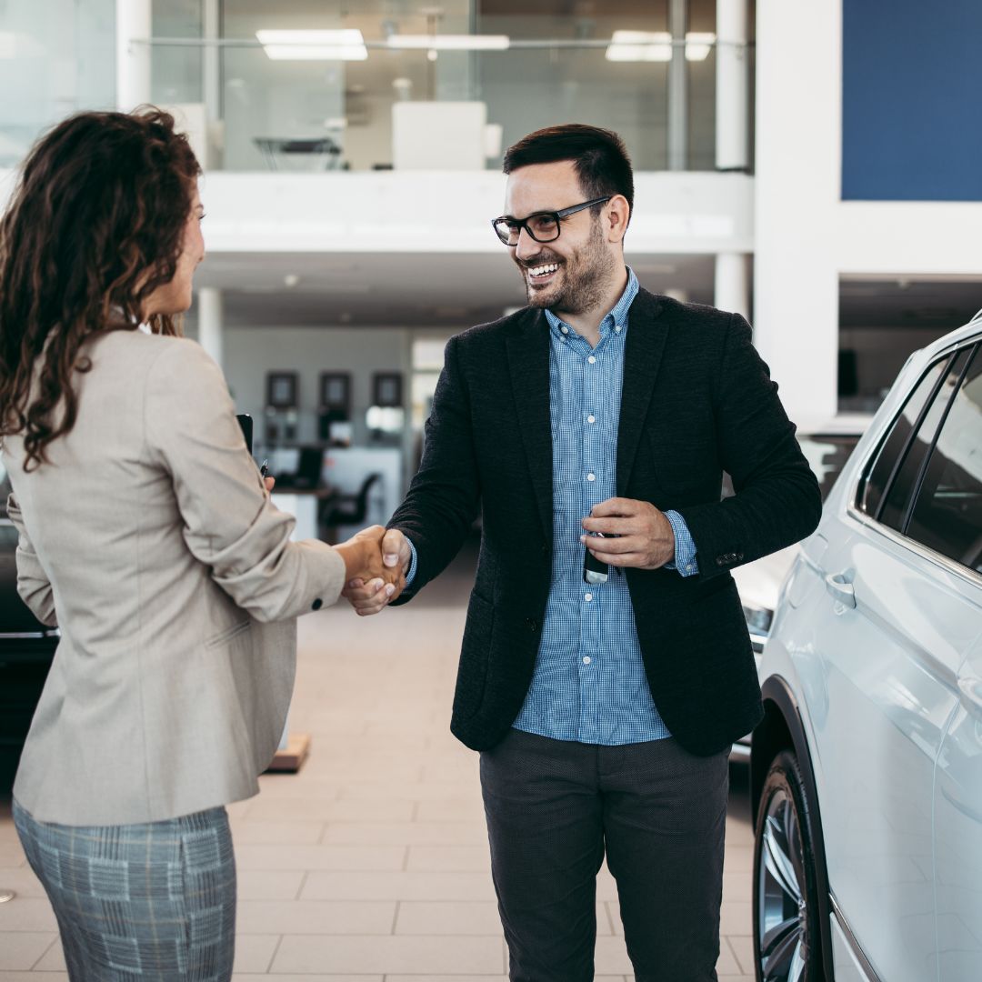 Car salesman shaking hands with customer