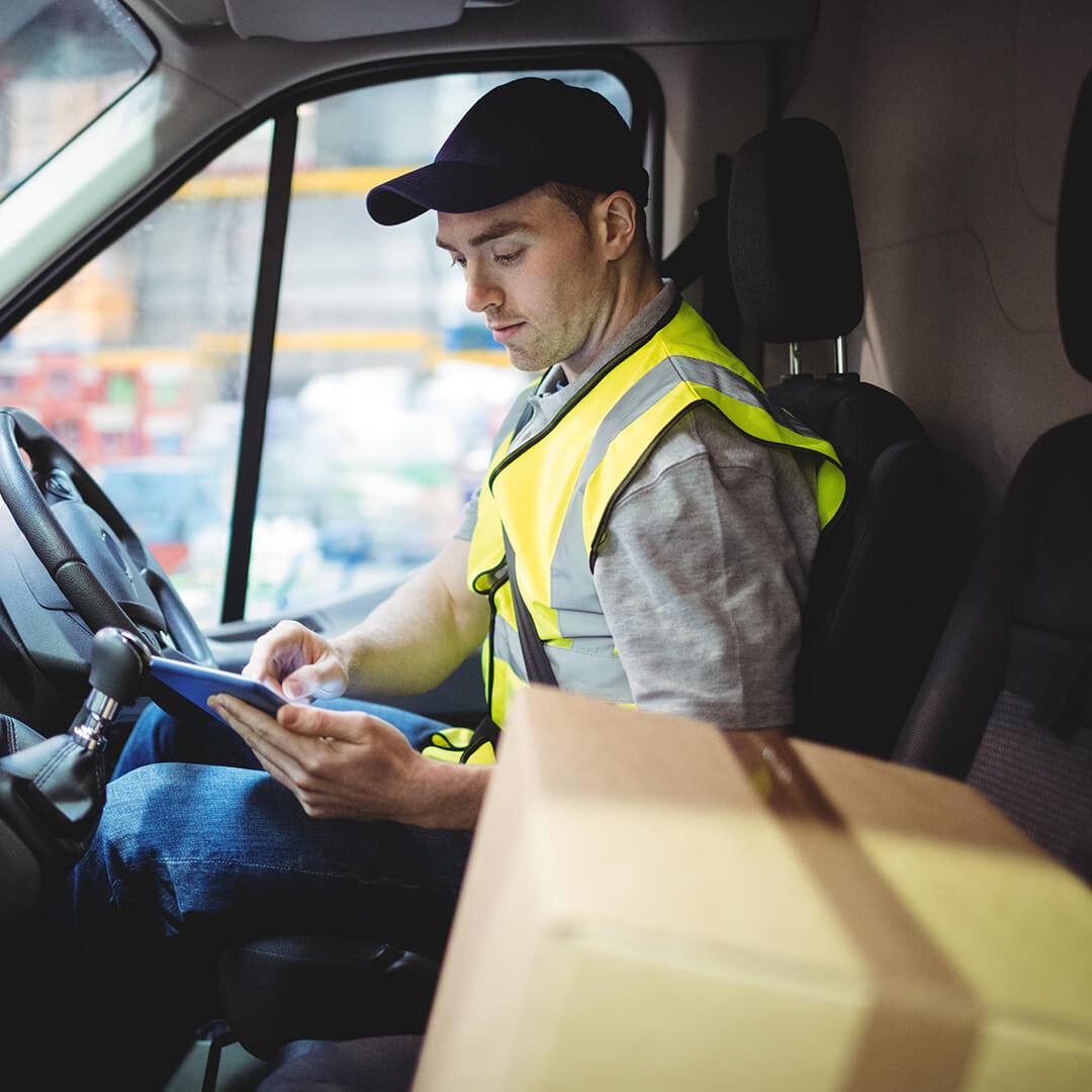 delivery truck driver with package next to him in truck