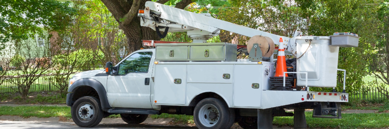 A white boom truck equipped with a person carrying bucket and storrage compartment upfits