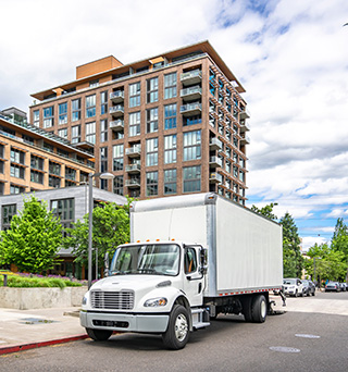 A medium duty box truck duty cab on a city street