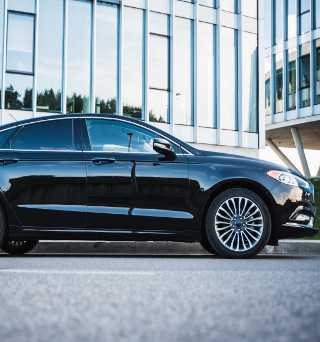 A black sedan parked in a parking space by a curb