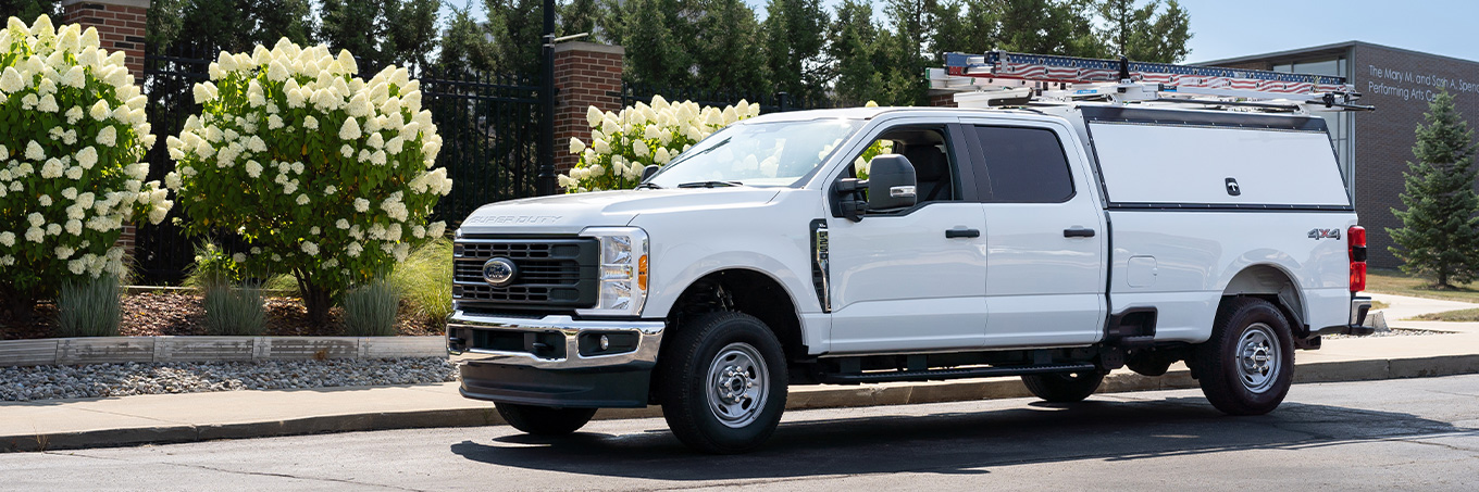 White pickup truck outside of a building with ladder racks and cap storage compartments