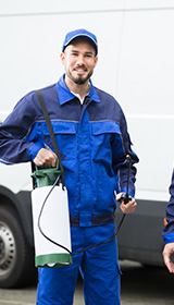 Two pest control workers standing in front of their vehicle