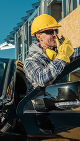 A man standing outside of a pickup truck with a hard hat on with the door open