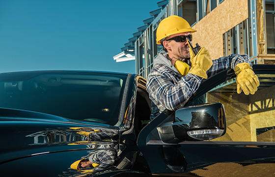 A man standing outside of a pickup truck with a hard hat on with the door open
