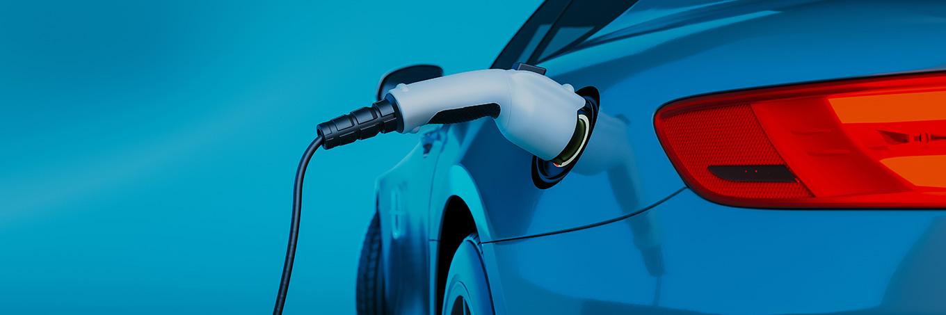 A blue electric sedan with a charger plugged into it on a gradient blue background