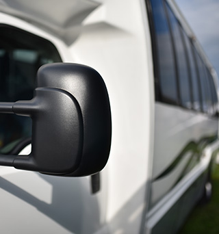 A close up of a white shuttle buss window and mirror